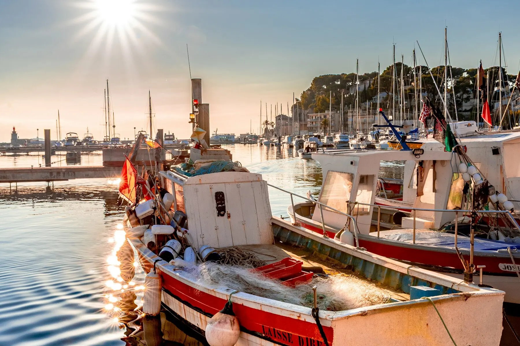 Fishing boats gathered in a harbour at sunrise.